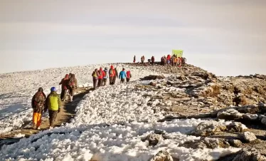A diverse group of individuals ascending a snowy mountain, surrounded by a pristine winter landscape.