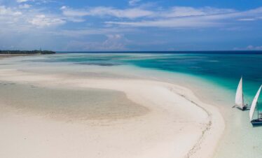 Two sailboats anchored on a pristine white sandy beach, after safari from dar es salaam